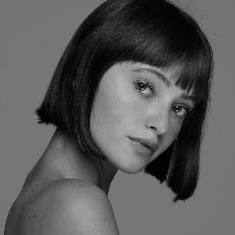 a black and white photo of a young woman with short hair and fringe bangs
