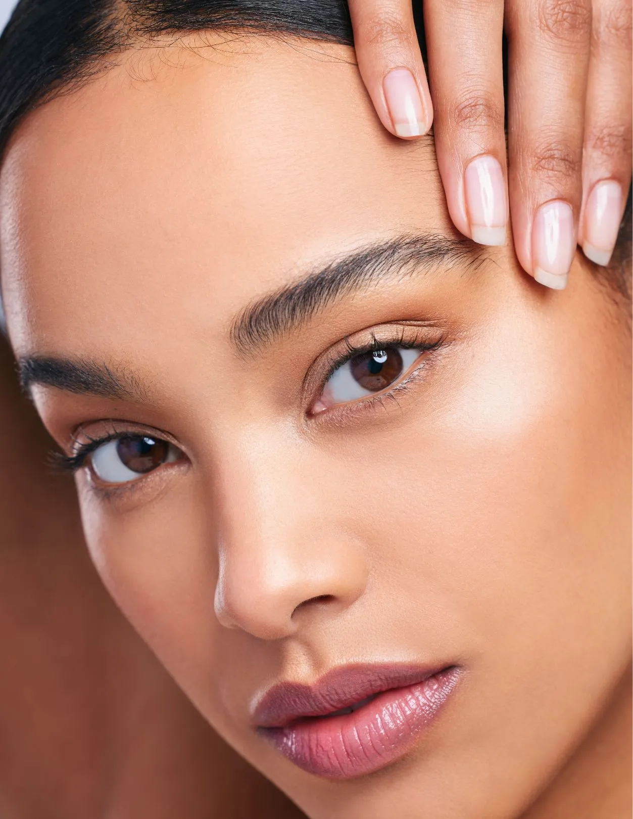 A tight shot of a young black woman pulling back her brow while looking at the camera