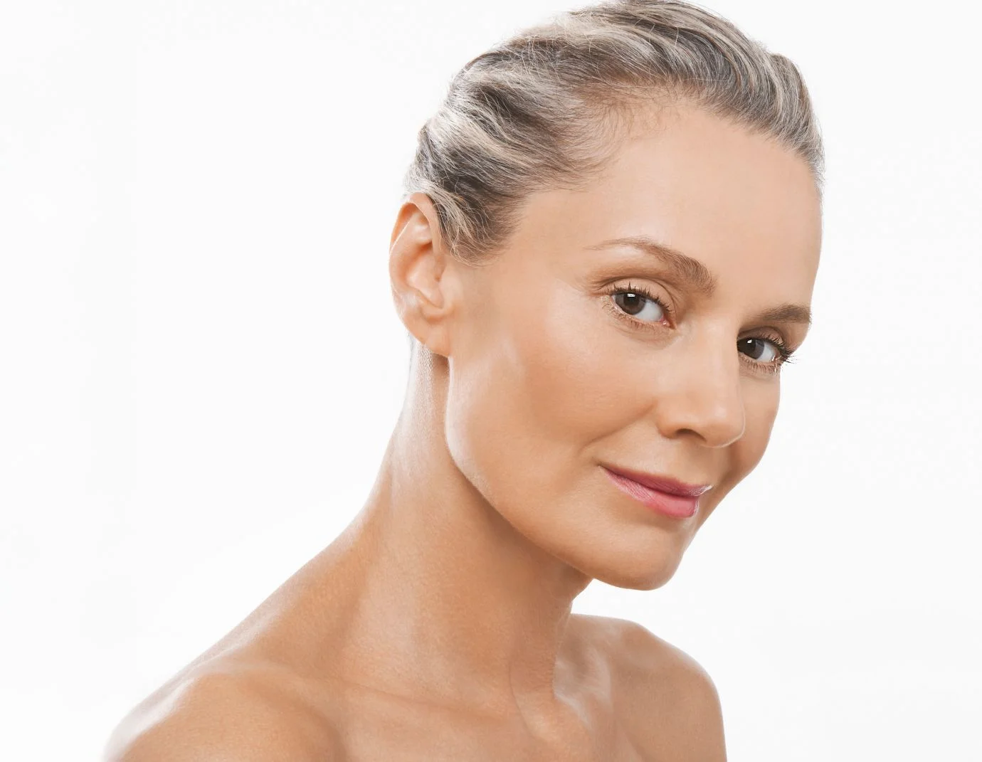 a mature woman with her hair pulled back standing against a white background