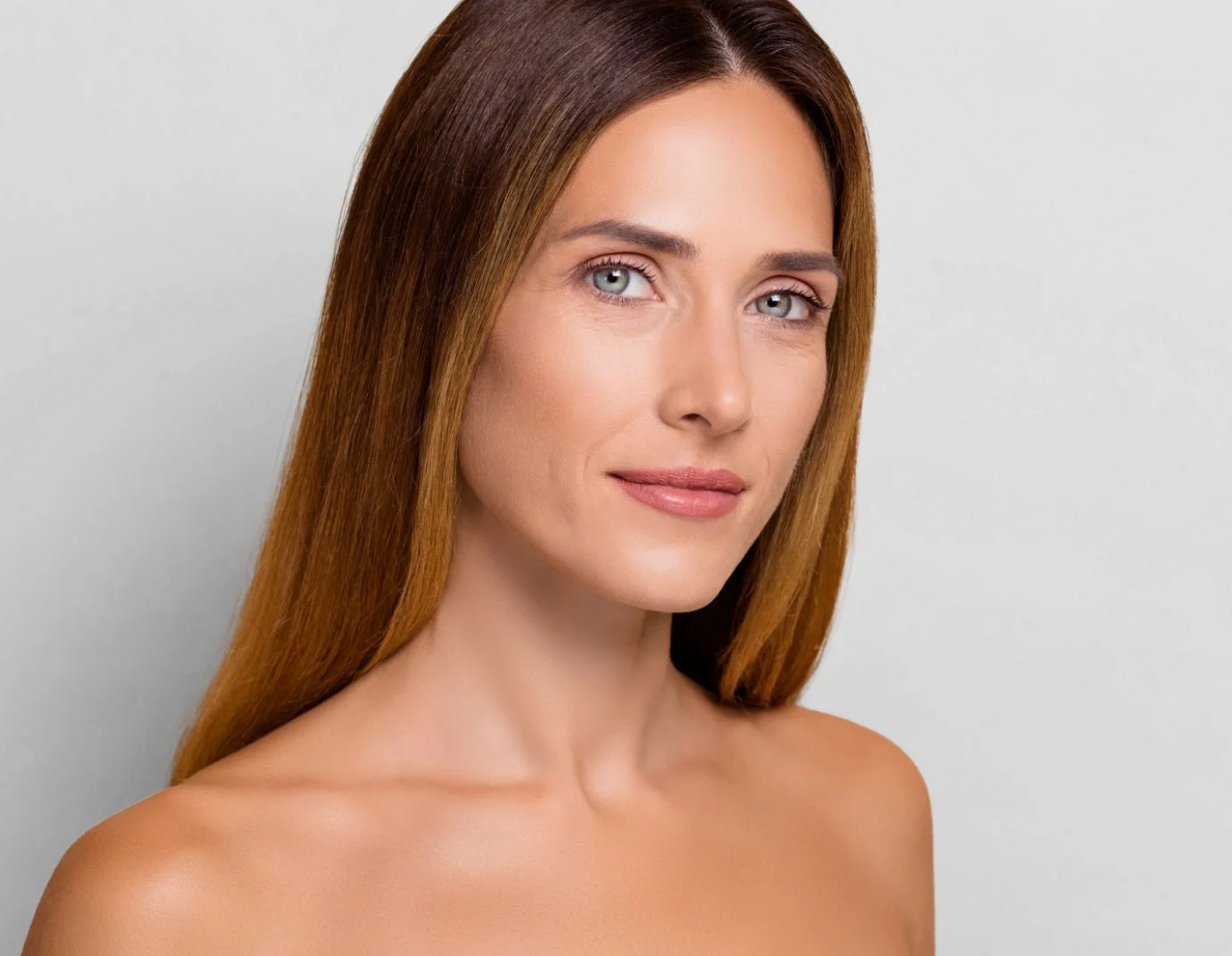 a woman with long brown hair against a light grey background