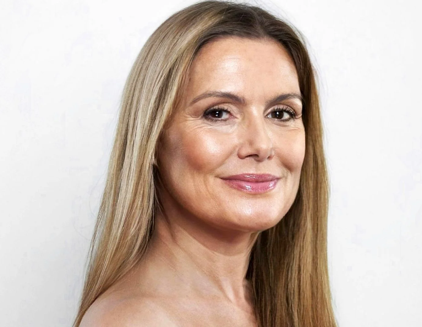 a mature woman with long blonde hair against a grey background